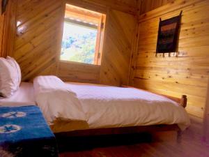 Dormitorio con cama y ventana en una cabaña de madera en Lysa House en Lao Cai