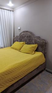 - un lit avec des draps et des oreillers jaunes dans une chambre dans l'établissement Квартира для семьи, à Almaty