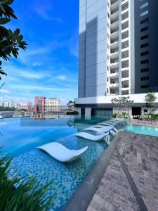 a hotel swimming pool with white chairs in front of a building at vista sentul residence share apartment with host in Kuala Lumpur