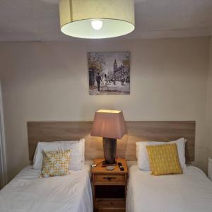 1 dormitorio con 2 camas y mesita de noche con lámpara en Stay Norwich Apartments Pottergate en Norwich