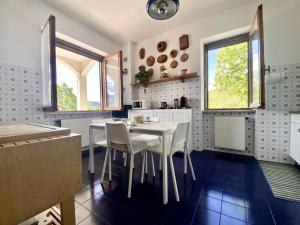 d'une cuisine avec une table, des chaises et des fenêtres. dans l'établissement La Casa del Bosco - Villa con vista panoramica su Bobbio e la Val Trebbia, à Bobbio