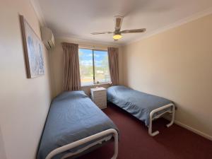 Un dormitorio con dos camas y una ventana. en Pelican Shore Villa 14 - Kalbarri WA, en Kalbarri 2 fotos más