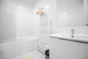 Baño blanco con lavabo y bañera en Casa Serena Paris Hôtel, en París