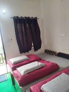 a bedroom with two beds with red sheets and a window at Hotel Narayana Residency in Gupta Kāshi
