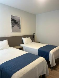 a hotel room with two beds with blue and white sheets at Hotel Casa costa in Mollendo