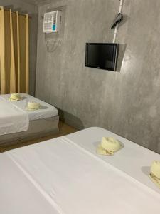 two beds in a room with a tv on the wall at FortuneBay Hotel in Tabuelan