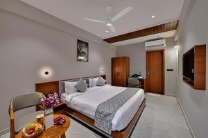 a hotel room with a bed and a television at Regenta Inn Motikhavdi Jamnagar in Jamnagar