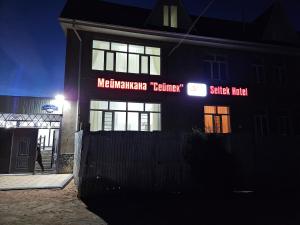 a building with a sign on the side of it at night at Seitek Hotel in Kochkor