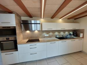 une cuisine avec des armoires blanches et un appareil en acier inoxydable dans l'établissement La Fontchaude (Cabrespine), à Cabrespine