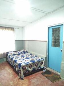 Bett in einem Zimmer mit blauer Tür in der Unterkunft Sweety Forest Villa in Passara