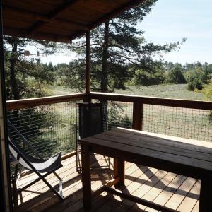 une terrasse couverte en bois avec un banc et une chaise dans l'établissement Domaine De Pradines, à Lanuéjols