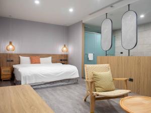 a bedroom with a bed and a chair and a table at Hotel Jiji Plus in Ch'ai-ch'iao-t'ou