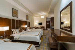 Habitación de hotel con 4 camas y espejo en Sulaf Luxury Hotel, en Amán