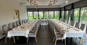 uma mesa longa com mesas e cadeiras brancas num quarto com janelas em Hotel Igloo em Krotoszyn