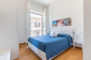 a white bedroom with a blue bed and a window at Elena House Apartments in Viareggio
