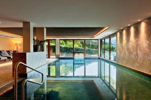 una piscina in una casa con finestre in vetro di Naturhotel Die Waldruhe a Chienes