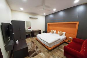 Hotel Mandakini Royale Near PVR Deep Cinema Hall Kanpur في كانبور: غرفة نوم بسرير واريكة حمراء