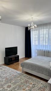 1 dormitorio con 1 cama y TV de pantalla plana en Dostyk en Almaty