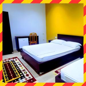 - une chambre avec un grand lit et un mur jaune dans l'établissement VILA LILI Guest House - Berat, à Berat