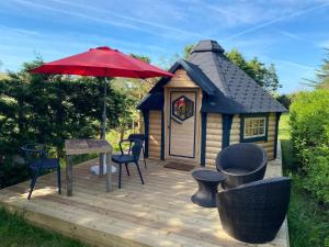 Cabaña pequeña con sombrilla roja, mesa y sillas en Camping Paradis le Moulin des Oies, en Belz