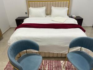 a bed with two blue chairs in a bedroom at Haima Hotel in Haymāʼ