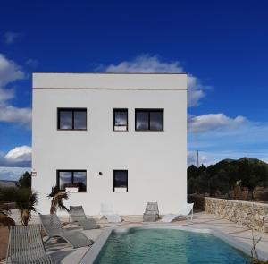 une maison blanche avec des chaises et une piscine dans l'établissement Casita del embalse con encanto, à Biar