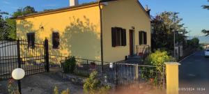 une petite maison jaune avec une clôture devant elle dans l'établissement La casa sul poggio, à Lubriano