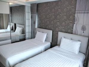 two beds in a hotel room with white sheets at ROYAL GRAND PATTAYA in Nong Prue