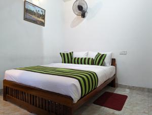 1 cama con sábanas verdes y blancas y ventilador en Brilliant View Home Stay en Ella