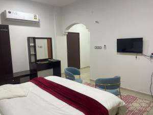 a bedroom with a bed and two chairs and a television at Haima Hotel in Haymāʼ