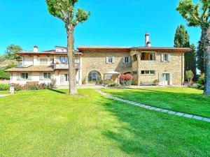 una grande casa in pietra con un cortile verde di Villa Giuliana ad Arezzo