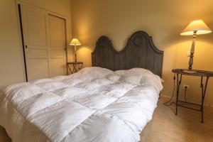 1 dormitorio con 1 cama blanca grande y cabecero de madera en Maison au cœur des corbières, en Saint-Laurent-de-la-Cabrerisse