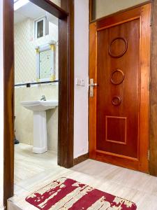a bathroom with a wooden door and a sink at Amazing Apartment Free Parking & Security in Dar es Salaam