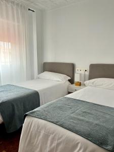 2 camas en una habitación de hotel con sábanas blancas y verdes en Pensión Del Sol, en Puerto Lumbreras