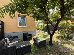 a patio with a couch and chairs under a tree at Viola Kisház in Siófok