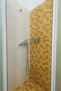 a bathroom with a shower with orange and yellow tiles at Studios Eliza in Livadi