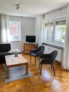sala de estar con 2 sillas y mesa en Ferienwohnung Gartenblick, en Amerang