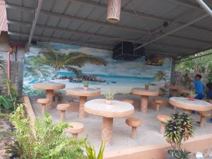 un grupo de mesas y bancos frente a un mural en golden anchor lodge en Corón