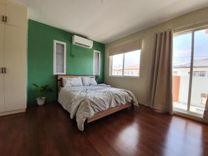 ein Schlafzimmer mit einem Bett mit einer grünen Wand in der Unterkunft Casa De Mira in Angeles