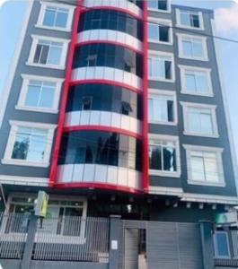 a tall building with a red and white at Amazing Apartment Free Parking & Security in Dar es Salaam