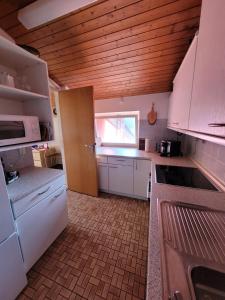cocina con electrodomésticos blancos y techo de madera en Waldhaus Max, en Bad Wildbad
