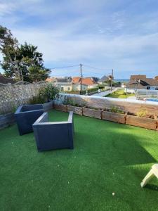 a garden with two blue benches on the grass at De la mer Chambre d'hôtes in Colleville-Montgomery