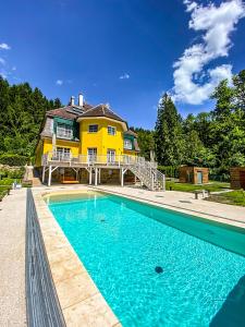 Scheibbs的住宿－Luxusvilla Österreich，黄色的房子,前面有一个游泳池