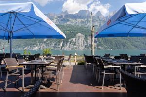 ein Restaurant mit Tischen, Stühlen und blauen Sonnenschirmen in der Unterkunft Hotel Schiffahrt in Mols