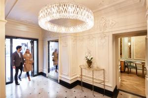 um homem e uma mulher a andar num corredor com um lustre em Hotel Zur Wiener Staatsoper em Viena