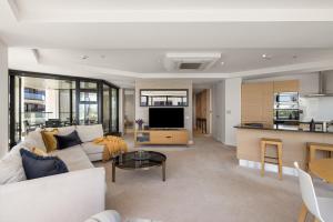 a living room with a couch and a table at Luxury Ocean & Harbour Views - Heated Pool, Main Beach & Gym in Mount Maunganui