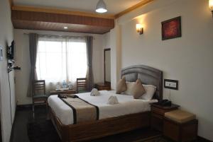 a bedroom with a large bed and a window at Hotel Kasturi Palace Darjeeling - Excellent Service Recommended in Darjeeling