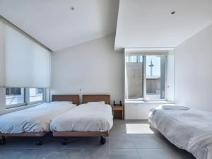 two beds in a room with two windows at ホテルトーイン京都 in Kyoto