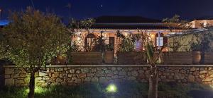 una casa con una pared de piedra y árboles por la noche en Sophia Town Square Areopoli, en Areopoli
