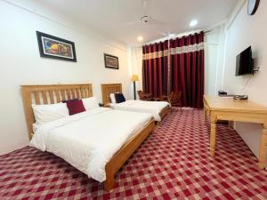 Habitación de hotel con 2 camas y escritorio en Hispar Hotel Skardu en Skardu